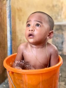 Ein Baby sitzt in einem orangenen Eimer mit Wasser