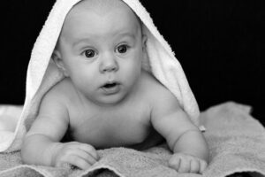 Ein Baby liegt auf einem Handtuch, während es ein anderes über dem Kopf hat