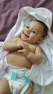 Ein grinselndes Baby liegt in einem Handtuch