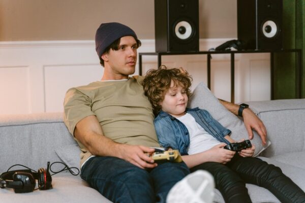 Ein Mann und ein Junge sitzen auf der Couch und haben Controller in der Hand