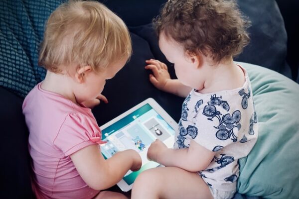 Zwei Kleinkinder sitzen vor einem Tablet