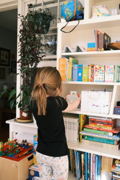 Ein Mädchen steht an einem Bücherregal.