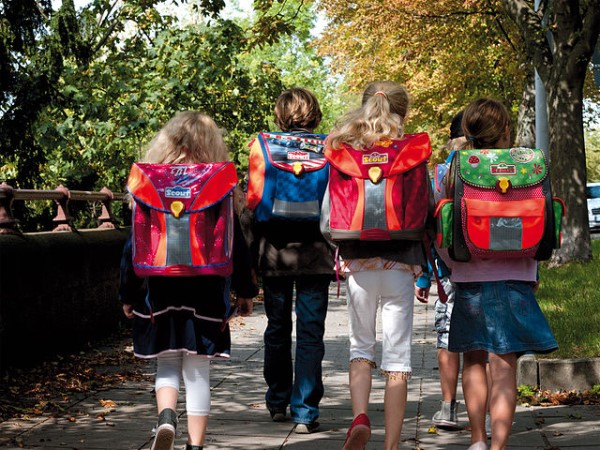 Vier Kinder tragen bunte Scout-Schulranzen. 