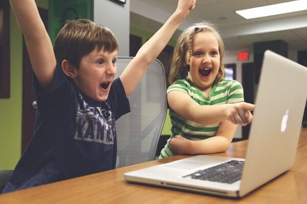Ein Junge und ein Mädchen freuen sich und schauen auf einen Laptop
