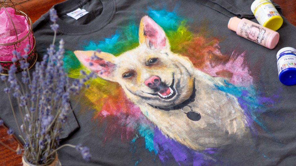 Ein T-Shirt, das mit Hundemotiv und buntem Hintergrund bemalt wurde