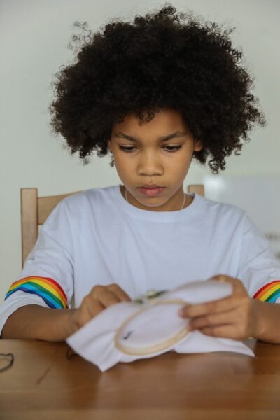 Ein Kind stickt konzentriert mit einem Stickrahmen
