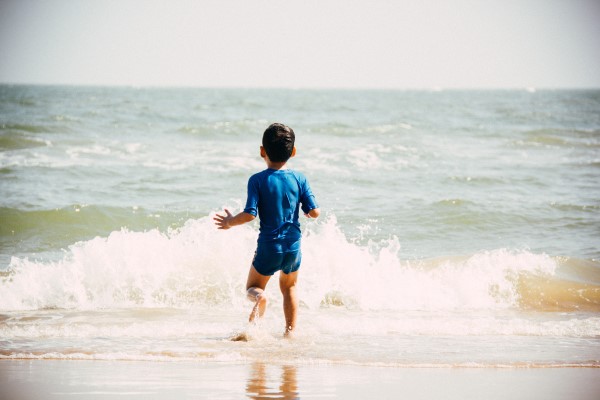 Ein Kind spielt am Strand mit den Wellen