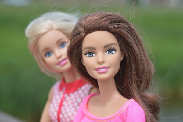 Zwei Barbies, eine brünett, die andere blond, schauen zum Betrachter.