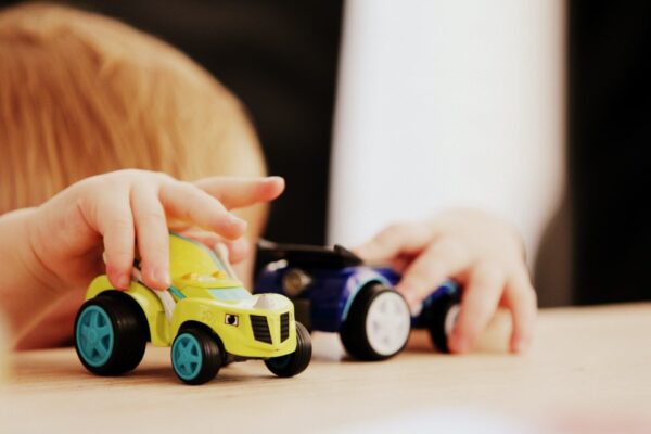 Kinderhände spielen mit zwei Spielzeugautos