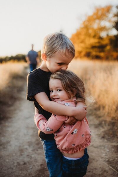 Ein Junge umarmt ein Mädchen auf einer Wiese