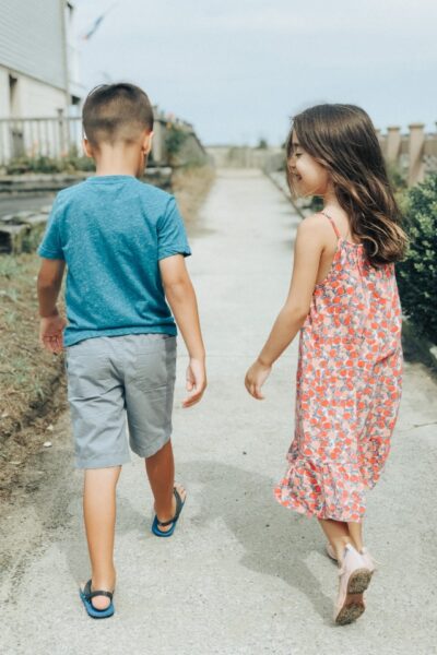 ein Junge und ein Mädchen gehen auf einem Fußweg von der Kamera weg