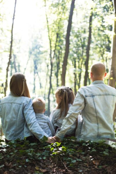 Eine Familie in Jeansjacken sitzt im Wald