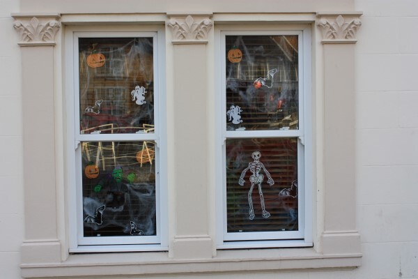 Zwei Fenster, die von innen mit Halloween-Figuren beklebt sind. 