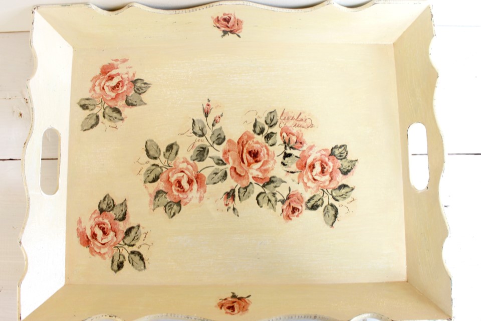 Ein helles Holztablett, das durch die Decoupage-Technik mit Rosenmotiven versehen wurde.